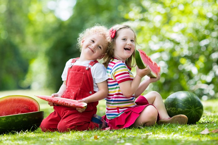Two Children Eating Watermelon on Grass