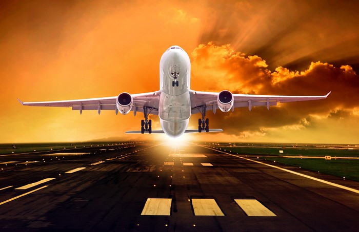 Airplane taking off on runway at sunset
