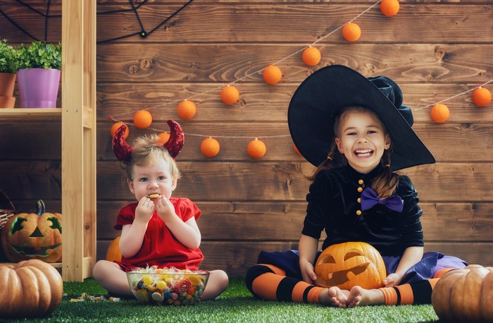Two girls in Halloween costumes with pumpkins