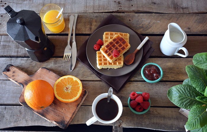 Breakfast with waffles, coffee, orange juice, and fruit