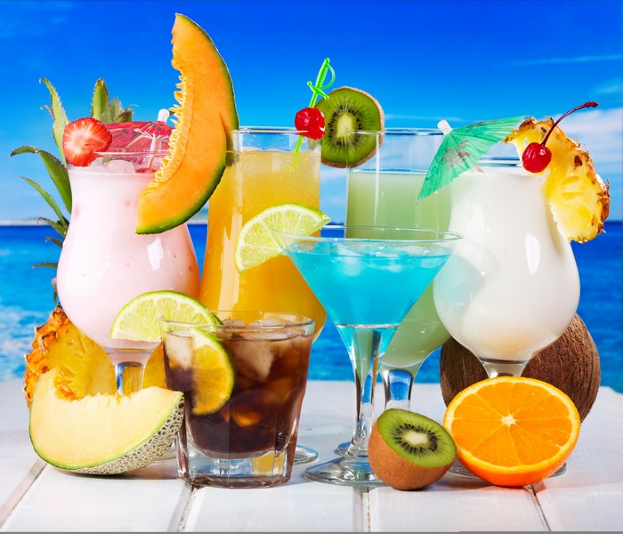 Assorted tropical cocktails with fruits on a beach background