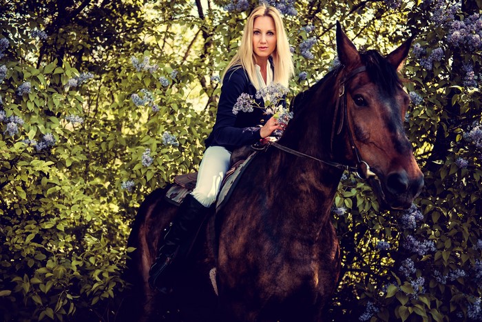 Blonde woman on a horse in a lilac bush