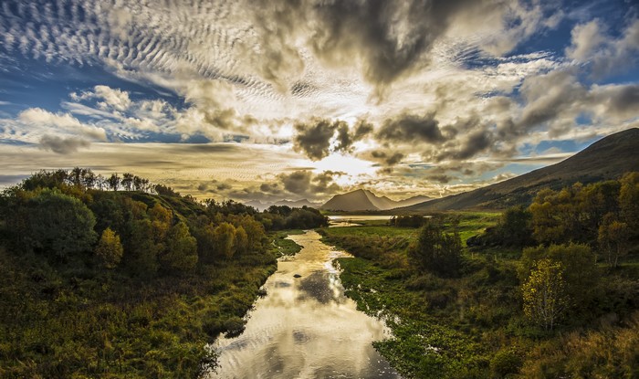 River flowing through a valley with mountains and clouds