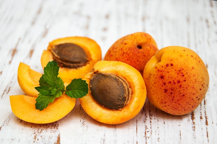 Apricots with mint leaves on a wooden surface