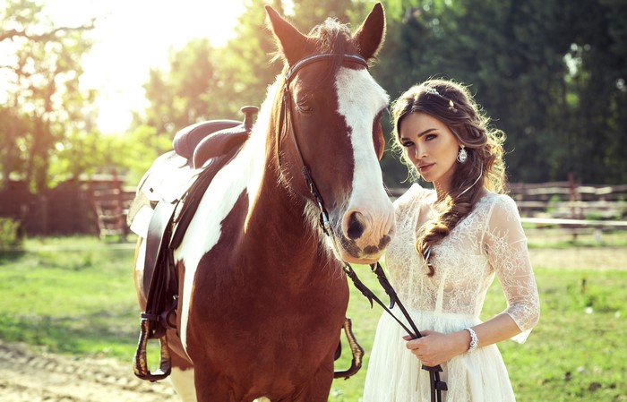 Woman in white dress with brown and white horse