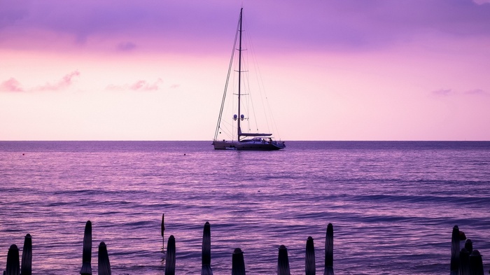 Sailboat on purple ocean at sunset