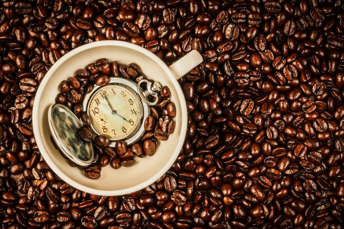 Pocket watch in a cup filled with coffee beans