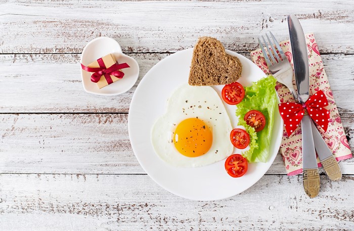 Heart-shaped fried egg breakfast with toast and tomatoes