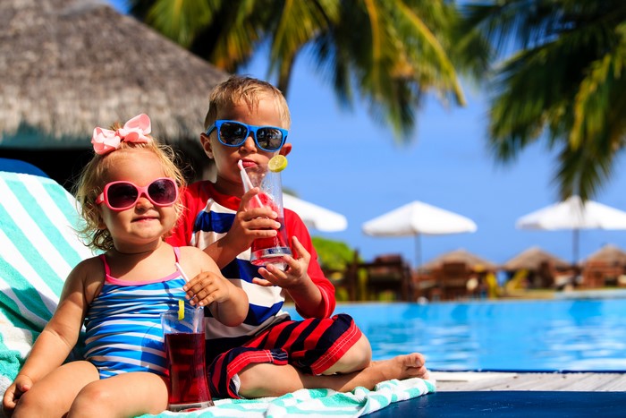 Two children with drinks by a pool