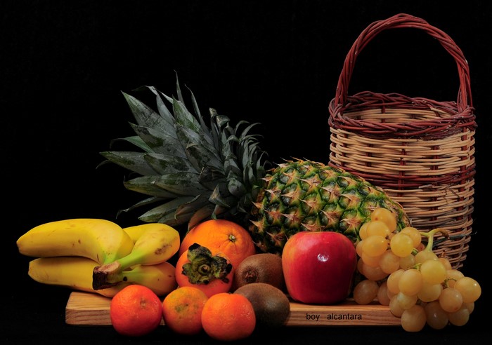 Fruit basket with pineapples, bananas, grapes, apples, and oranges