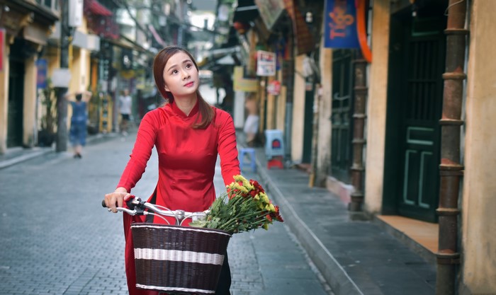 Woman in red dress with bicycle and flowers