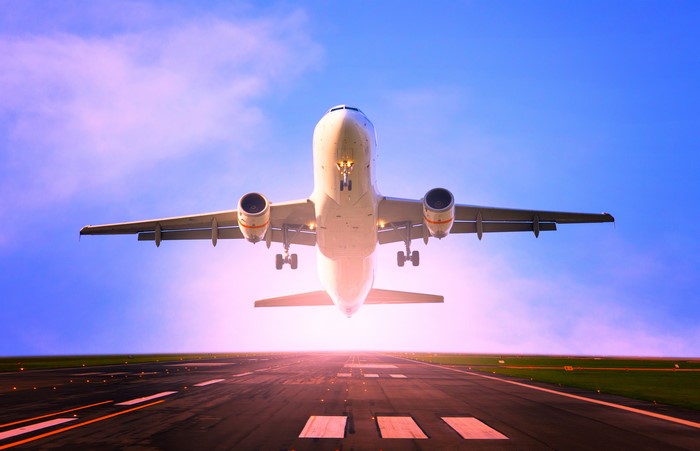 Airplane taking off from runway at sunset