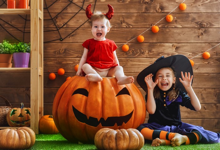 Two young girls in Halloween costumes with a pumpkin