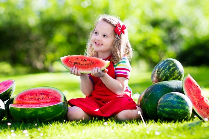 Girl eating watermelon in grass