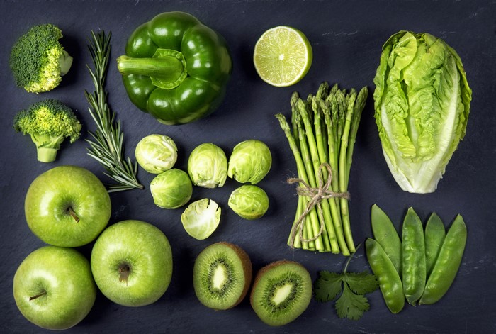 Green vegetables and fruits on black background