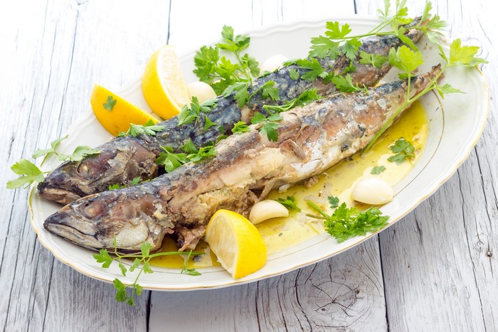 Two baked mackerels with lemon and parsley on a plate