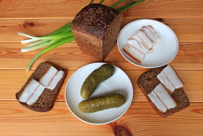 Bread, Salo, Cucumbers, and Green Onions on a Wooden Table