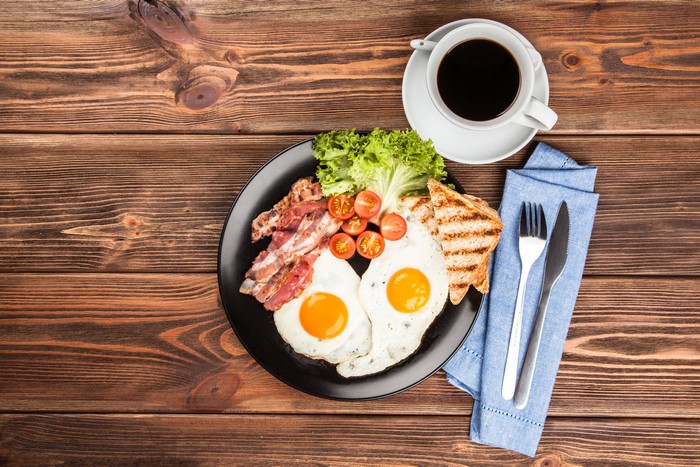 Breakfast with fried eggs, bacon, toast, and coffee