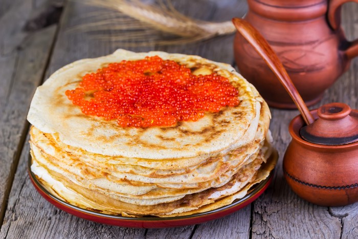 Pancakes with red caviar and clay pots