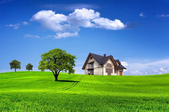 A modern house on a green hill under a blue sky