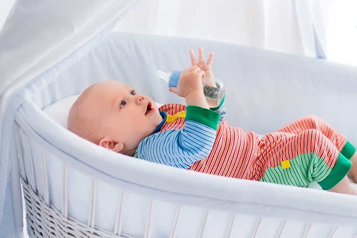 Baby holding a bottle in a crib
