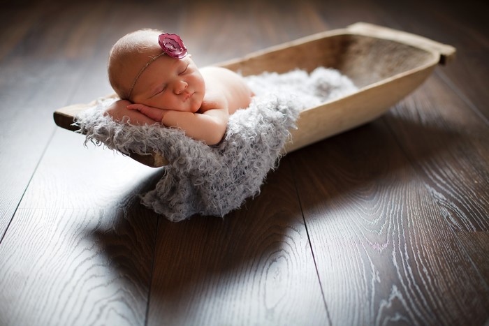 Newborn baby sleeping in a wooden bowl