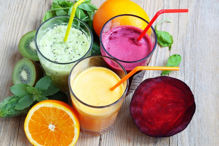 Three glasses of colorful smoothies with fruits and vegetables