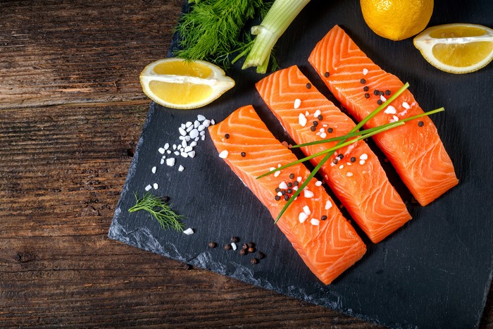 Salmon fillets with lemon and herbs on slate