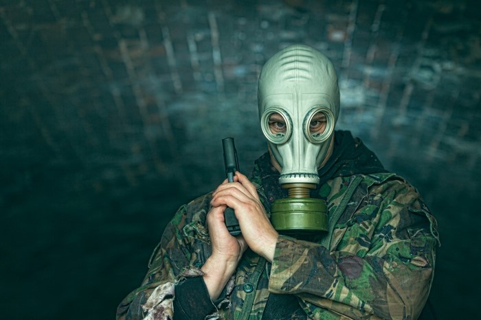 Man in gas mask holding a pistol