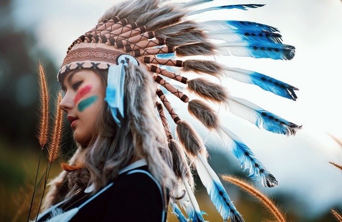 Woman wearing a Native American headdress with face paint