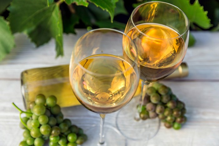Two glasses of white wine with grapes and bottle