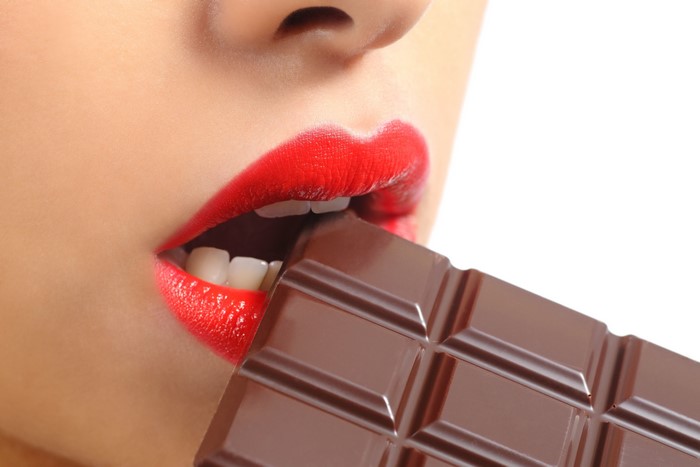 Woman with red lips eating chocolate bar