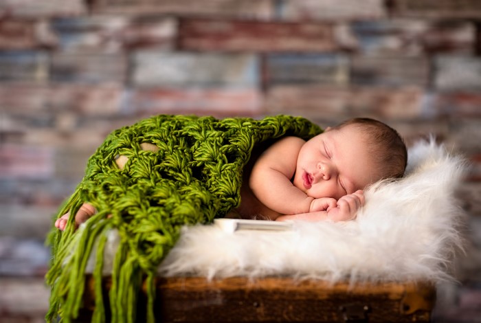 Newborn baby sleeping wrapped in a green blanket
