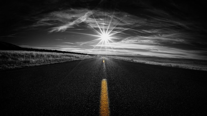 Road with yellow line and sun