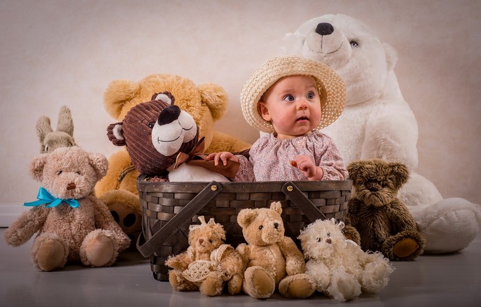 Baby in a hat with teddy bears in a basket