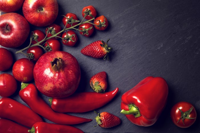 Red fruits and vegetables on a dark surface
