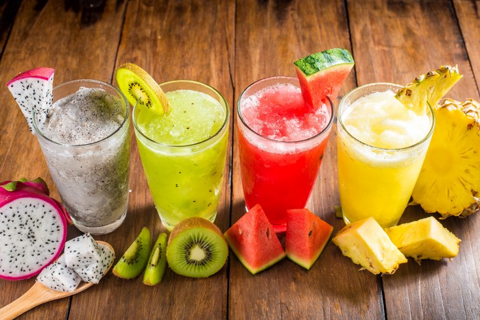 Four fruit smoothies with fresh fruit garnishes