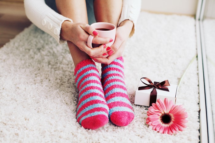 Woman holding coffee cup with gift and flower
