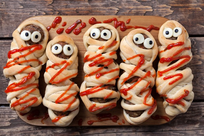 Mummy meatloaf with ketchup on a cutting board