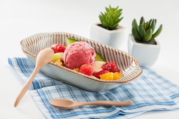 Fruit salad with strawberry ice cream and spoons