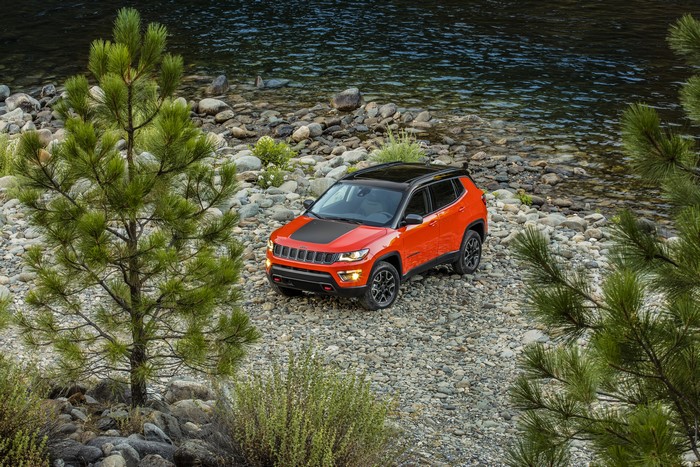 Orange Jeep Compass Trailhawk on rocky river bank