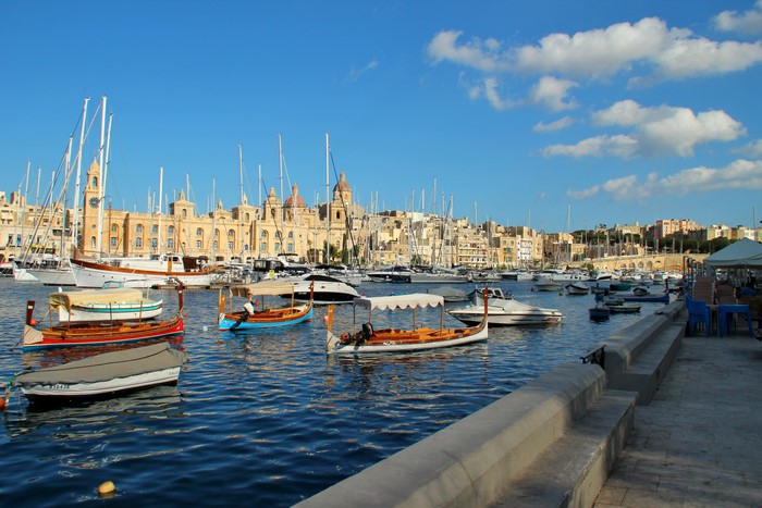Boats in a harbor with buildings and sailboats in Malta