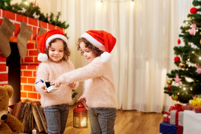 Two little girls in Santa hats with Christmas gifts