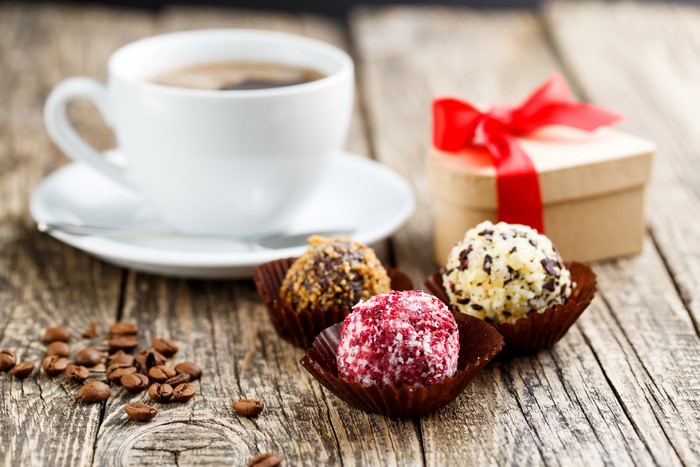 Coffee cup, candies, and gift box on wooden planks