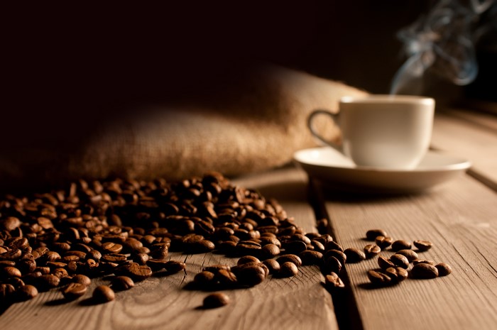 Coffee beans, cup, saucer, and burlap sack on wood