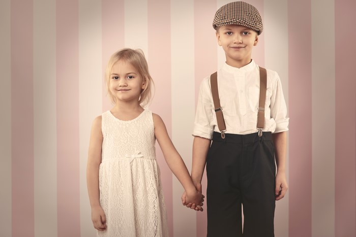 Two children in vintage clothing holding hands
