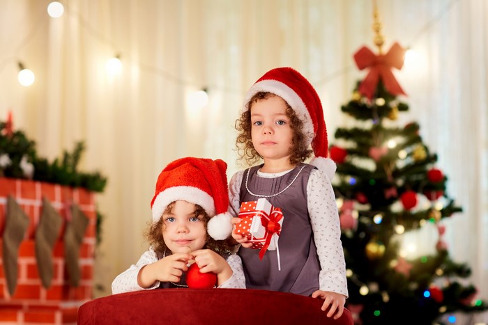 Two little girls in Santa hats with Christmas gifts
