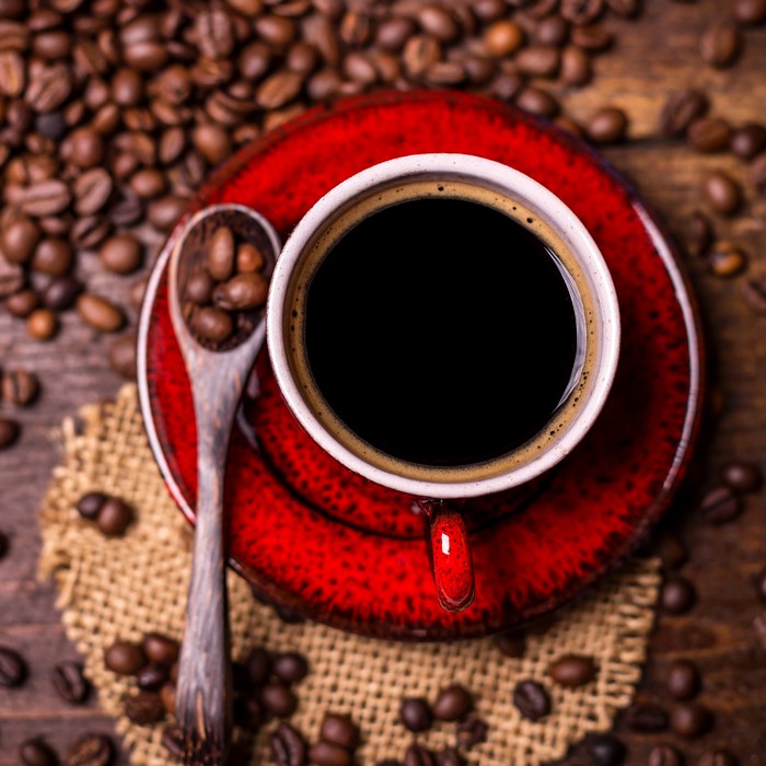 A cup of coffee with coffee beans and a spoon