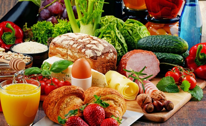 Still-life of breakfast with juice, bread, ham, cheese, and fruits