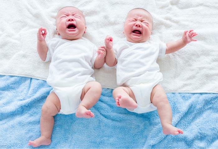 Two crying infants lying down
